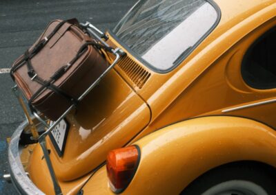 Yellow vintage car with luggage on the trunk.